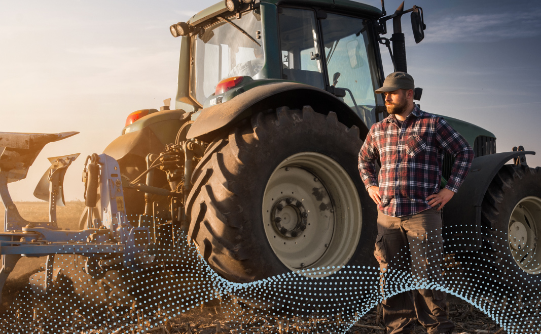 a farmer stands proudly in front of a tractor