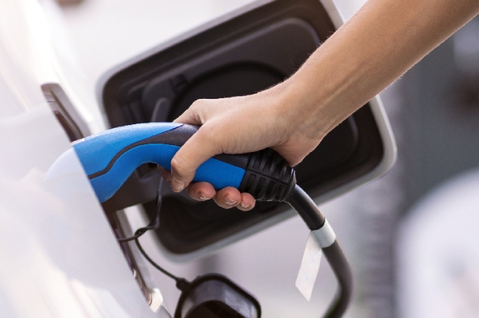 close up on a hand operating an electric vehicle charging nozzle