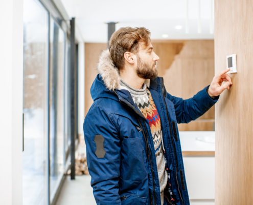 Man adjusting temperature with thermostat at home
