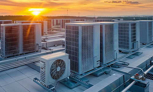 three air conditioning units on a rooftop at sunset