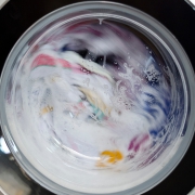 sudsy clothes mid-cycle in a front-loading washing machine