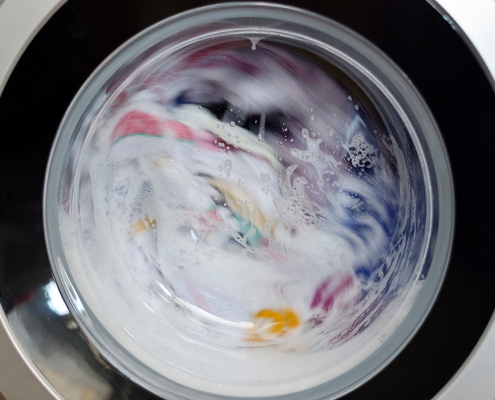 sudsy clothes mid-cycle in a front-loading washing machine