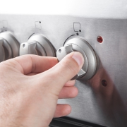 two fingers pinch a stovetop gas range dial