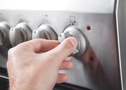 two fingers pinch a stovetop gas range dial