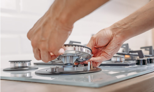 two hands adjust the parts of stovetop gas burner
