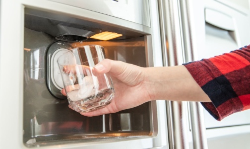 a person fills a glass with ice from a refrigerator with Robertshaw ice maker valve