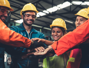five warehouse workers stand in a circle, smiling, hands in the center