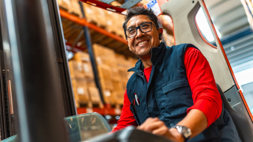 a smiling forklift driver works in a warehouse